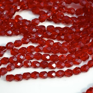 May include: A strand of red faceted glass beads. The beads are small and have a shiny finish.