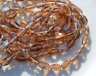 May include: A strand of iridescent brown oval glass beads. The beads are faceted and have a shimmery finish.