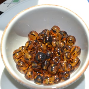 May include: A white bowl filled with brown and black striped glass beads.