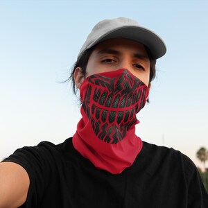 May include: A red face covering with a black graphic design resembling a skeletal grin. The face covering is worn around the neck and lower face. The person in the image is wearing a gray baseball cap and a black t-shirt.