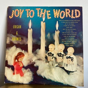 May include: Vintage Christmas album cover titled "Joy to the World." The cover features four lit candles, angel figurines, and the album's song list. The album's title is in a festive font, with a blue background.