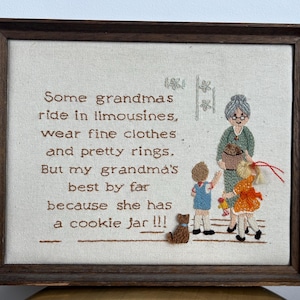 May include: Embroidered artwork in a wooden frame. The artwork features text that reads "Some grandmas ride in limousines...but my grandma's best by far because she has a cookie jar!!!" with an illustration of a grandma and children.