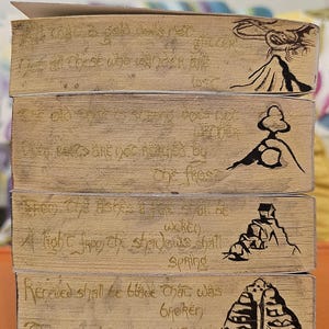 May include: Four wooden blocks with etched text and illustrations. The text includes phrases like "A light from the shadows shall spring" and "The crownless again shall be king." Each block features a different black ink illustration.