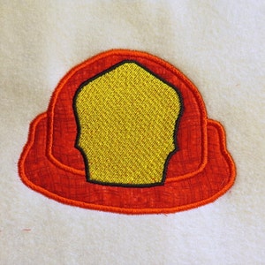 Pode incluir: Etiqueta bordada de capacete de bombeiro vermelho e amarelo. O capacete é contornado em preto.