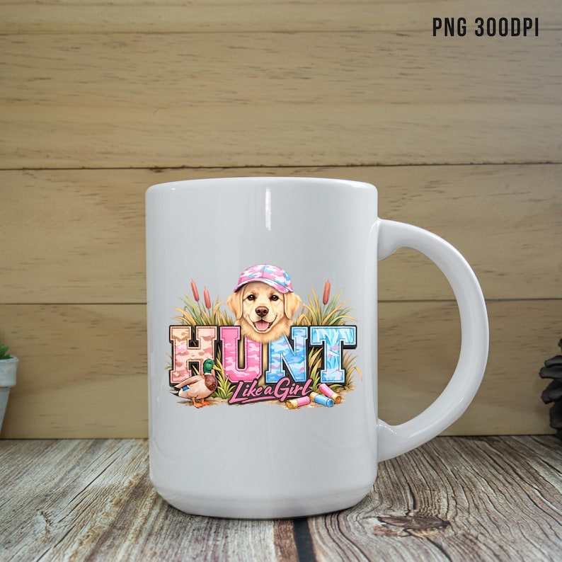 May include: White ceramic mug with a wraparound graphic. The graphic features a golden retriever wearing a camouflage hat, the word "HUNT" in pink and blue letters, and the phrase "Like a Girl". A duck and shotgun shells are also included.
