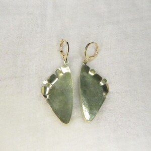 May include: A pair of dangle earrings featuring semi-circular, mottled sage green stone segments set in polished gold-tone metal frames. Each earring is suspended from a gold-tone leverback closure, showcasing a smooth, curved edge and a flat, straight top.