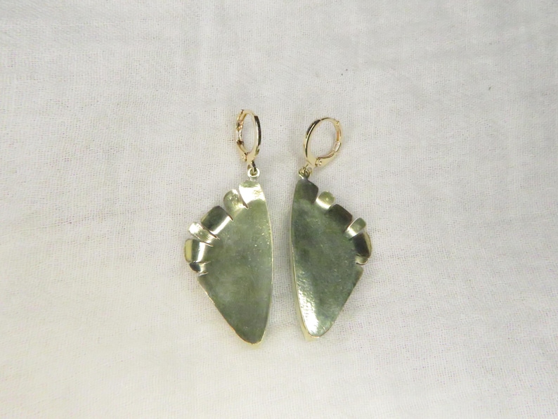 May include: A pair of dangle earrings featuring semi-circular, mottled sage green stone segments set in polished gold-tone metal frames. Each earring is suspended from a gold-tone leverback closure, showcasing a smooth, curved edge and a flat, straight top.