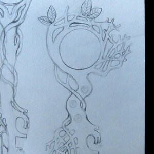 May include: A graphite pencil sketch on white paper depicting two key designs. The keys feature intricate, organic, tree-like structures with intertwined branches, roots, and circular heads. Small leaves are visible at the top of the keys.