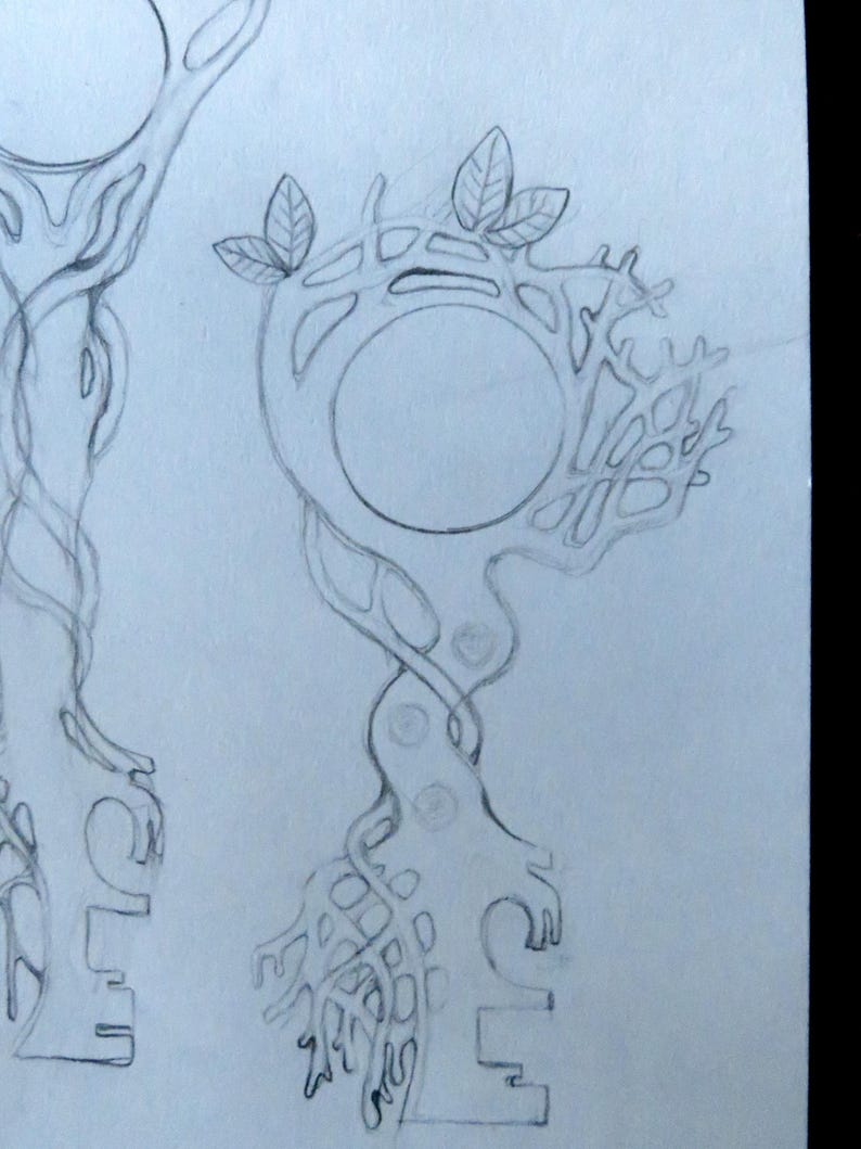 May include: A graphite pencil sketch on white paper depicting two key designs. The keys feature intricate, organic, tree-like structures with intertwined branches, roots, and circular heads. Small leaves are visible at the top of the keys.