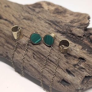 May include: A pair of gold-toned ear cuffs connected by delicate chains to two circular stud earrings featuring green malachite stone inlays with distinct banded patterns. The jewelry set includes two plain metal cuffs and two matching studs.