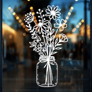 Könnte beinhalten: Weiße Strichzeichnung eines Blumenstraußes in einem Einmachglas. Die Blumen umfassen Gänseblümchen und Knospen. Das Glas ist mit einer Schleife gebunden. Der Hintergrund ist eine verschwommene Ansicht eines Gebäudes.