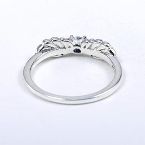 K&ouml;nnte beinhalten: Ein silberner Ring mit floralem Design. Der Ring hat einen zentralen, klaren Edelstein und kleinere Steine, die in die floralen Elemente eingesetzt sind. Das Band ist glatt und poliert und erzeugt ein zartes und elegantes Aussehen.