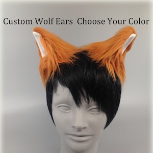May include: A pair of custom wolf ears with a black base and orange tips. The ears are attached to a white headband. The headband is worn on a mannequin with black hair.