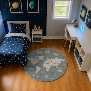 Puede incluir: Un dormitorio infantil con un juego de cama azul marino y blanco con estampado de estrellas, un escritorio blanco y una alfombra redonda con un diseño de mapa del mundo. La habitación tiene una pared azul con obras de arte de planetas y un suelo de madera.
