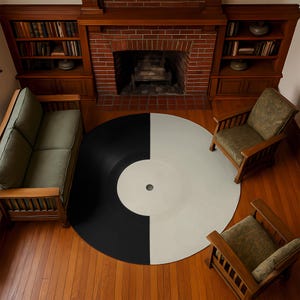 Può includere: Un grande tappeto rotondo progettato per assomigliare a un disco in vinile. Il tappeto è diviso in due metà: una nera e una bianco sporco. Il tappeto è posizionato su un pavimento in legno, circondato da mobili.