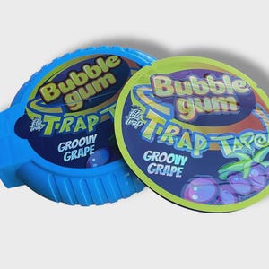 May include: Two packs of bubble gum with the text "Bubble Gum Trap Groovy Grape". One pack is blue, the other is green and yellow. The packaging features grape illustrations.