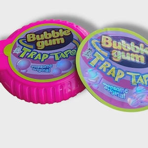 May include: A bright pink Bubble Gum Trap Tape dispenser and a matching oval package. The packaging features the words "Bubble Gum Trap Tape" in a playful font, with bubble graphics and the words "awesome original".