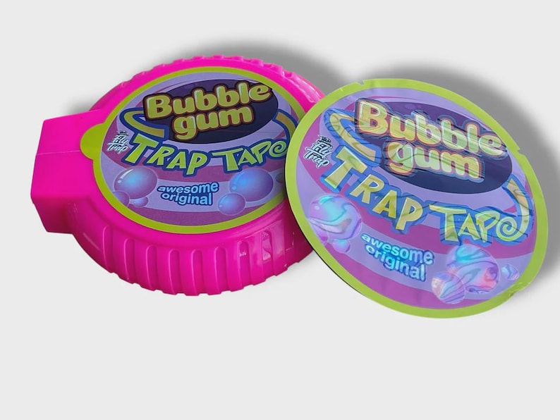 May include: A bright pink Bubble Gum Trap Tape dispenser and a matching oval package. The packaging features the words "Bubble Gum Trap Tape" in a playful font, with bubble graphics and the words "awesome original".