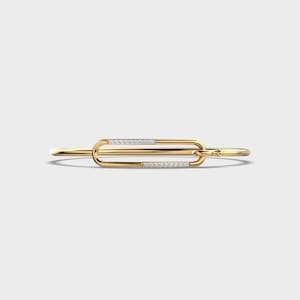May include: A gold bangle bracelet with a diamond-encrusted clasp. The clasp is shaped like a rectangle with rounded edges.
