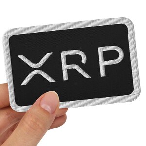 May include: A black embroidered patch with white stitching that says "XRP" in all caps.