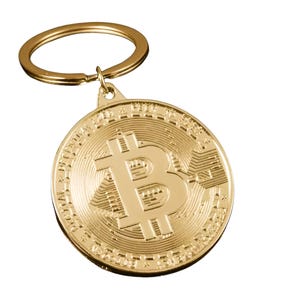 May include: A gold-coloured Bitcoin keyring. The round pendant features the Bitcoin symbol and detailed design. The keyring includes a gold-coloured ring for attaching keys.