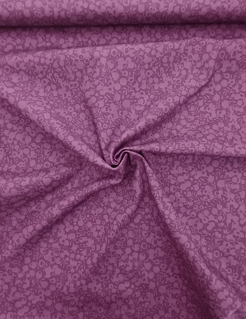 Może przedstawiać: Fioletowy materiał z małym białym wzorem kwiatowym. Materiał jest złożony i ma miękką, fakturowaną fakturę.