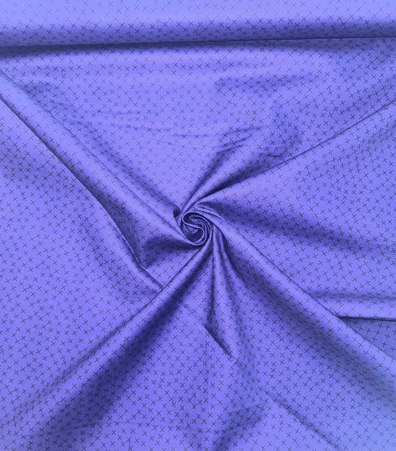 May include: A close-up of a purple fabric with a repeating pattern of small black crosses.