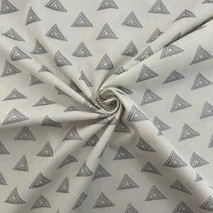 Puede incluir: Tela blanca con un patr&oacute;n repetido de tri&aacute;ngulos conc&eacute;ntricos grises.