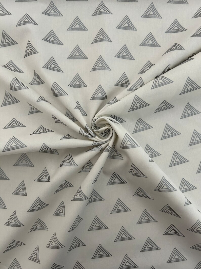 Puede incluir: Tela blanca con un patr&oacute;n repetido de tri&aacute;ngulos conc&eacute;ntricos grises.