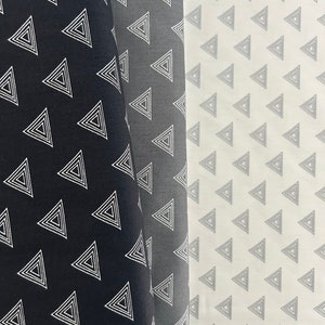 Könnte beinhalten: Zwei Stoffmuster mit einem geometrischen Muster aus weißen konzentrischen Dreiecken auf schwarzem und grauem Hintergrund.