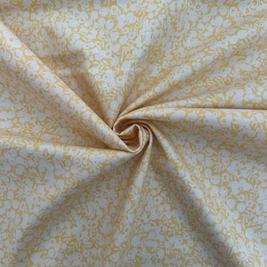 Pu&ograve; includere: Un tessuto giallo con un motivo floreale bianco. Il tessuto &egrave; piegato e ha una consistenza morbida.