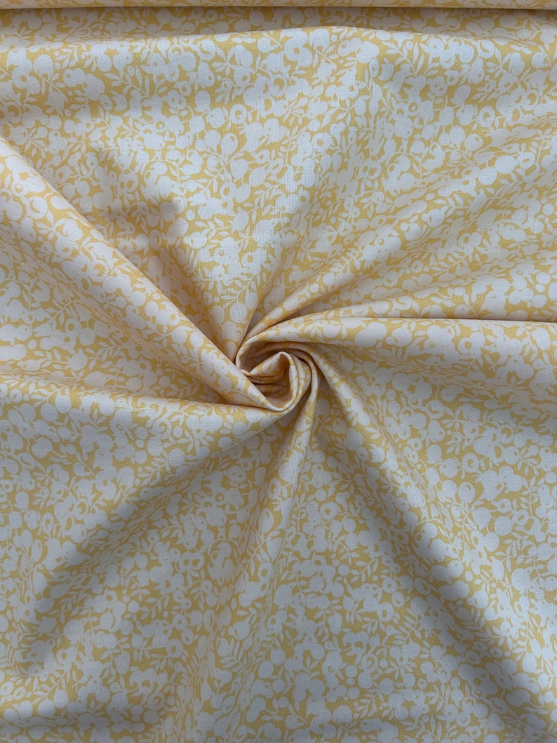 Pu&ograve; includere: Un tessuto giallo con un motivo floreale bianco. Il tessuto &egrave; piegato e ha una consistenza morbida.