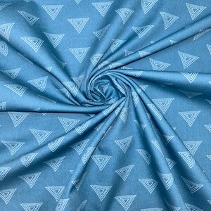 May include: A close-up shot of blue fabric with a repeating pattern of white, nested triangles. The fabric is gathered and folded, creating a swirling effect. The triangles are evenly spaced across the material.