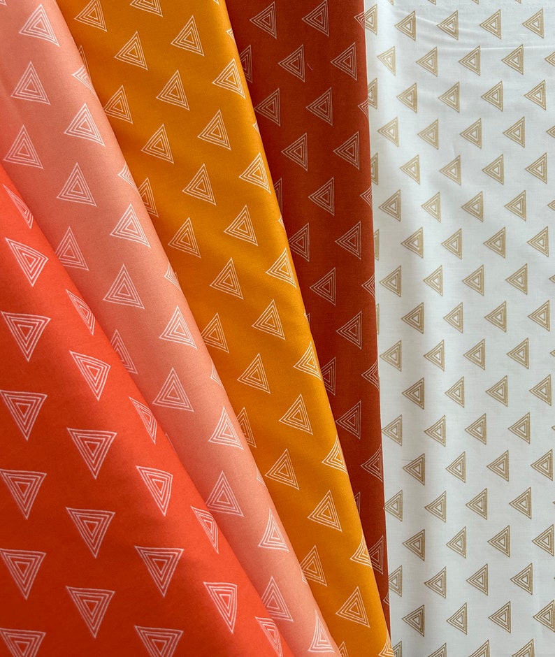 Puede incluir: Cuatro muestras de tela con un patr&oacute;n geom&eacute;trico de tri&aacute;ngulos blancos sobre fondos de colores diferentes: naranja, melocot&oacute;n, amarillo y blanco.