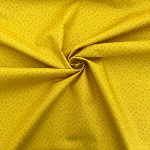 Puede incluir: Una tela amarilla con un sutil patr&oacute;n de rejilla. La tela est&aacute; doblada y drapeada, mostrando su textura.