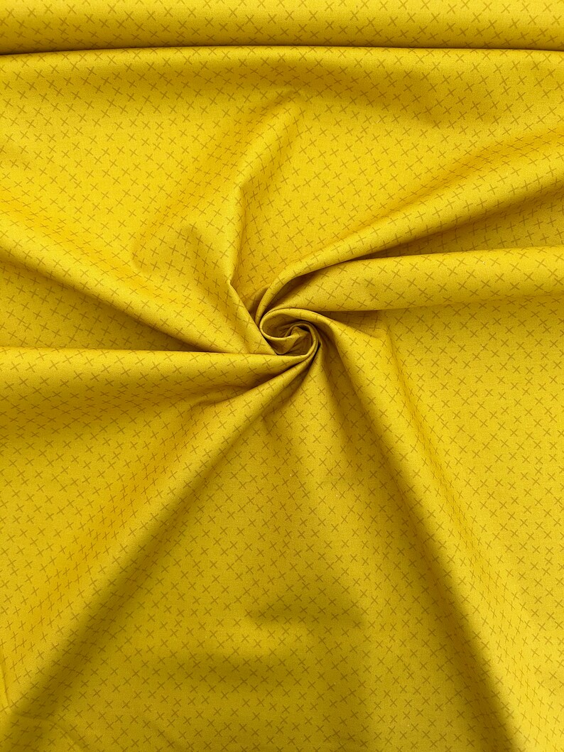 Puede incluir: Una tela amarilla con un sutil patr&oacute;n de rejilla. La tela est&aacute; doblada y drapeada, mostrando su textura.