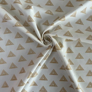 Puede incluir: Tela blanca con un patr&oacute;n repetitivo de tri&aacute;ngulos dorados. Los tri&aacute;ngulos est&aacute;n formados por l&iacute;neas conc&eacute;ntricas.