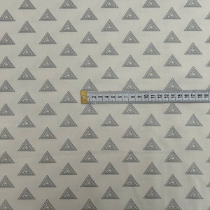 Puede incluir: Tela blanca con un patr&oacute;n repetido de tri&aacute;ngulos conc&eacute;ntricos grises. Una regla se coloca sobre la tela, mostrando medidas en pulgadas.