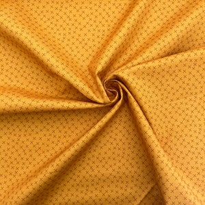 Puede incluir: Primer plano de una tela amarilla con un patr&oacute;n repetitivo de peque&ntilde;as cruces rojas. La tela est&aacute; doblada y drapeada, mostrando su textura.