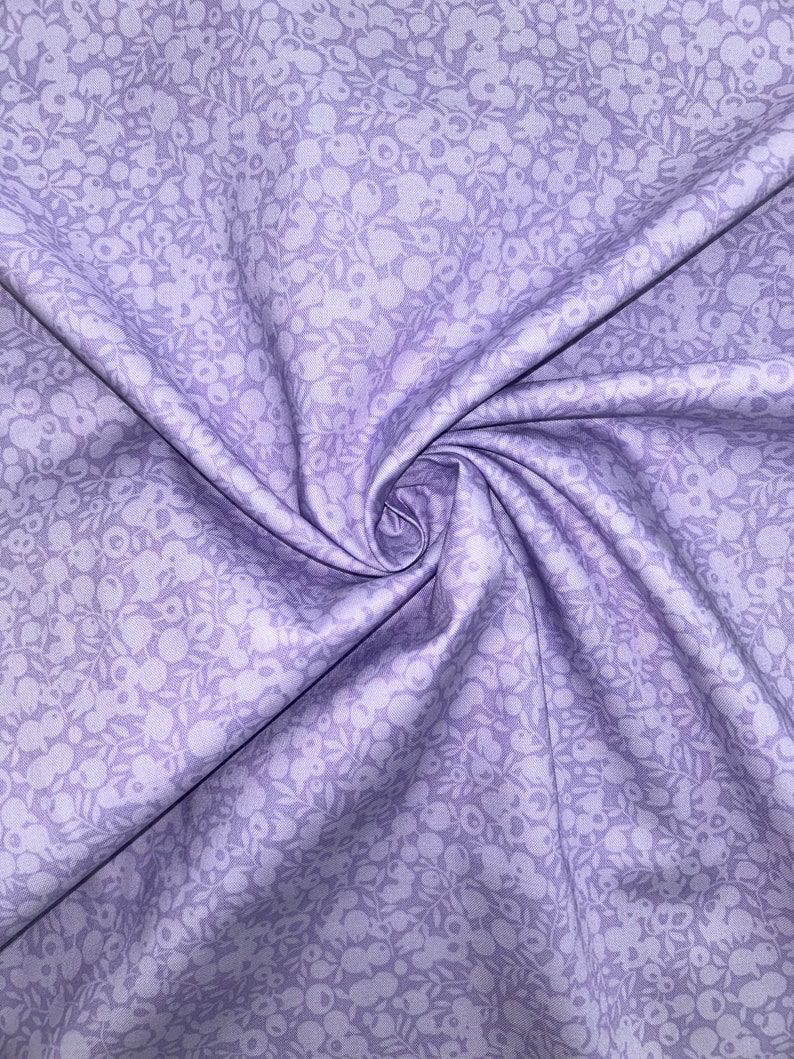 Może przedstawiać: Zbliżenie na lawendowy materiał z białym wzorem kwiatowym. Materiał jest złożony i ma fakturę.