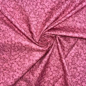 Może przedstawiać: R&oacute;żowy materiał z białym wzorem kwiatowym. Materiał jest złożony i ma miękką, fakturowaną fakturę.