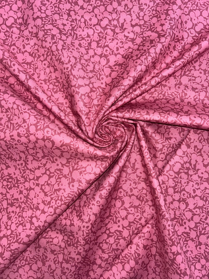 Może przedstawiać: R&oacute;żowy materiał z białym wzorem kwiatowym. Materiał jest złożony i ma miękką, fakturowaną fakturę.
