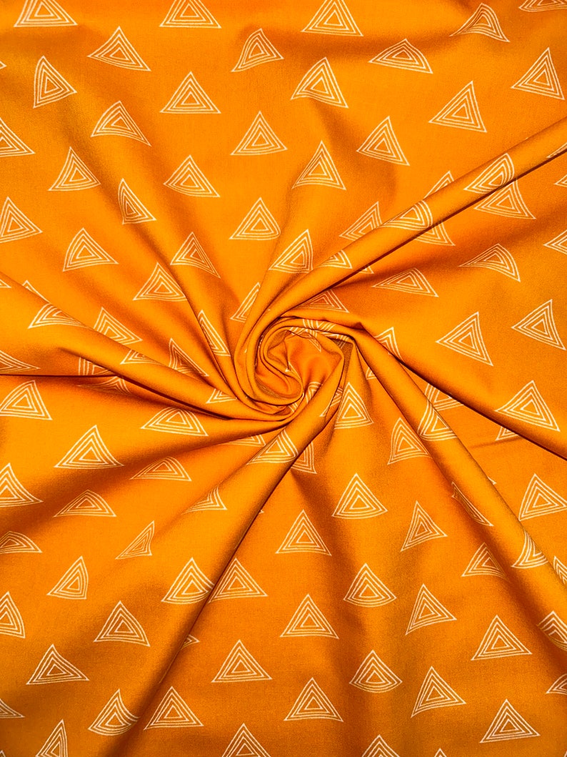 Puede incluir: Tela naranja con un patr&oacute;n geom&eacute;trico blanco de tri&aacute;ngulos repetidos. La tela est&aacute; doblada y texturizada.