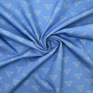 May include: Light blue fabric with a repeating pattern of white outlined triangles. The fabric is gathered and folded, creating shadows and texture. The triangles are evenly spaced across the material.