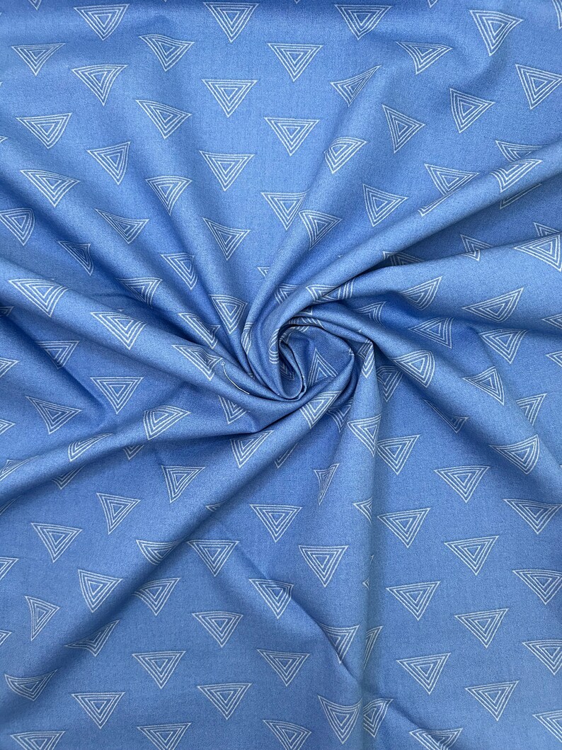 May include: Light blue fabric with a repeating pattern of white outlined triangles. The fabric is gathered and folded, creating shadows and texture. The triangles are evenly spaced across the material.