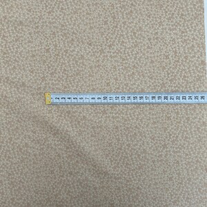 May include: Beige fabric with a repeating pattern of small brown triangles.