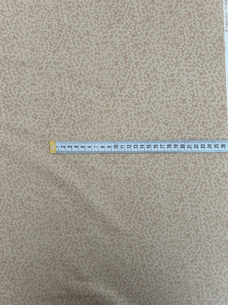 May include: Beige fabric with a repeating pattern of small brown triangles.