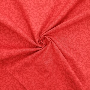 Może przedstawiać: Czerwony materiał z małym białym wzorem kwiatowym. Materiał jest złożony i ma miękką, fakturowaną fakturę.