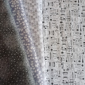 Könnte beinhalten: Drei Stoffmuster mit verschiedenen Mustern. Das erste Muster ist dunkelgrau mit einem weißen Blumenmuster. Das zweite Muster ist hellgrau mit einem weißen Tupfenmuster. Das dritte Muster ist weiß mit einem schwarz-weißen Muster aus küchenbezogenen Wörtern und Bildern, darunter "Bake", "Flour", "Mix it" und "Eat Dessert First".