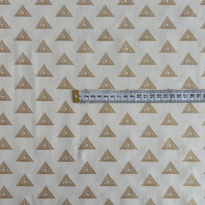 Puede incluir: Tela blanca con un patr&oacute;n repetido de tri&aacute;ngulos de contorno dorado. Los tri&aacute;ngulos est&aacute;n superpuestos y tienen un brillo sutil.